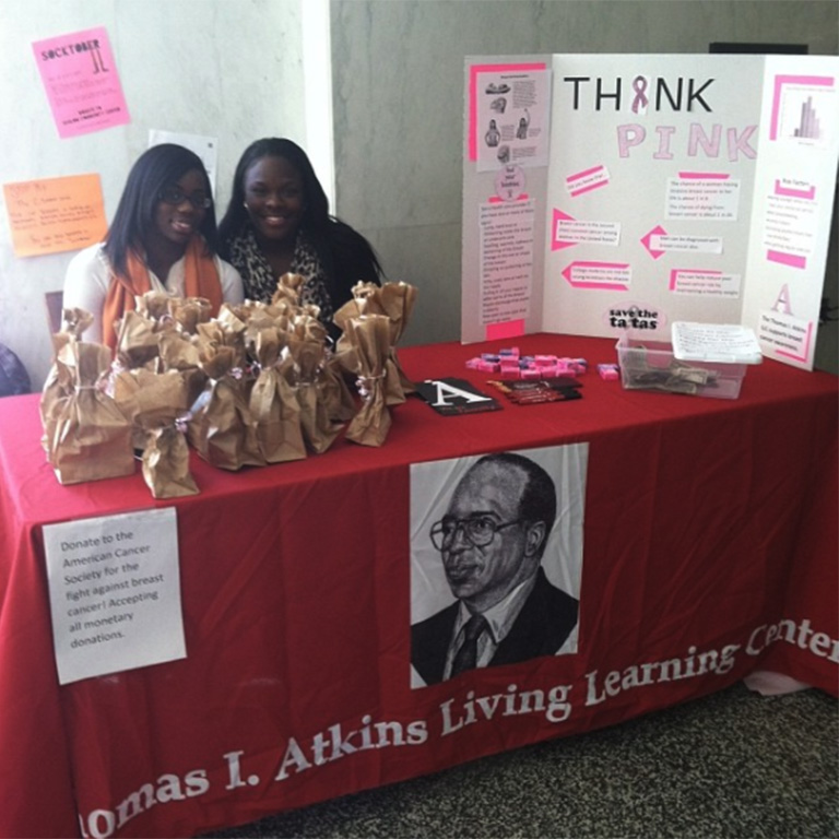 Two students smiling at an Atkins display table during an event. 