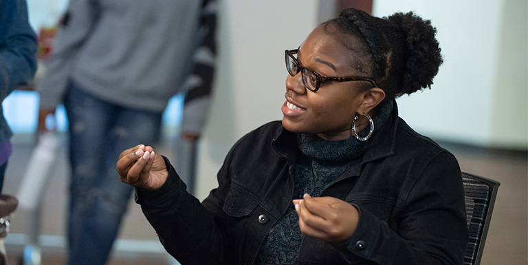 A student gesturing during a discussion.