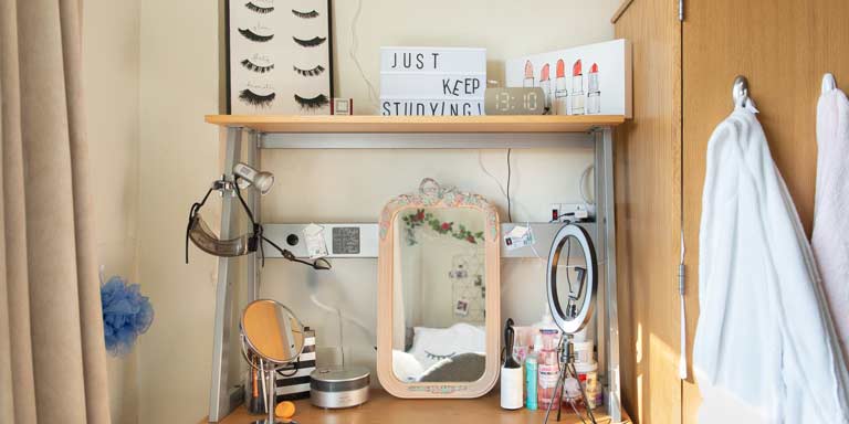 A desk with many beauty products and mirrors.